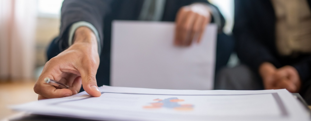 An image of paperwork being reviewed in a meeting